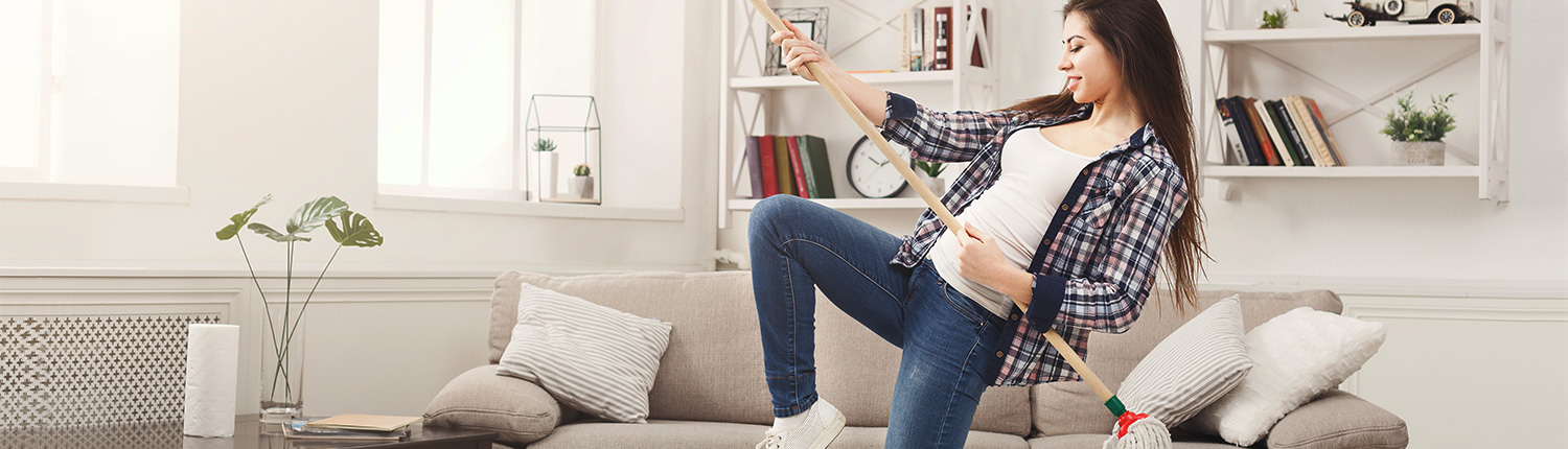 Frau hält Wischmop wie Gitarre - Frühjahrsputz