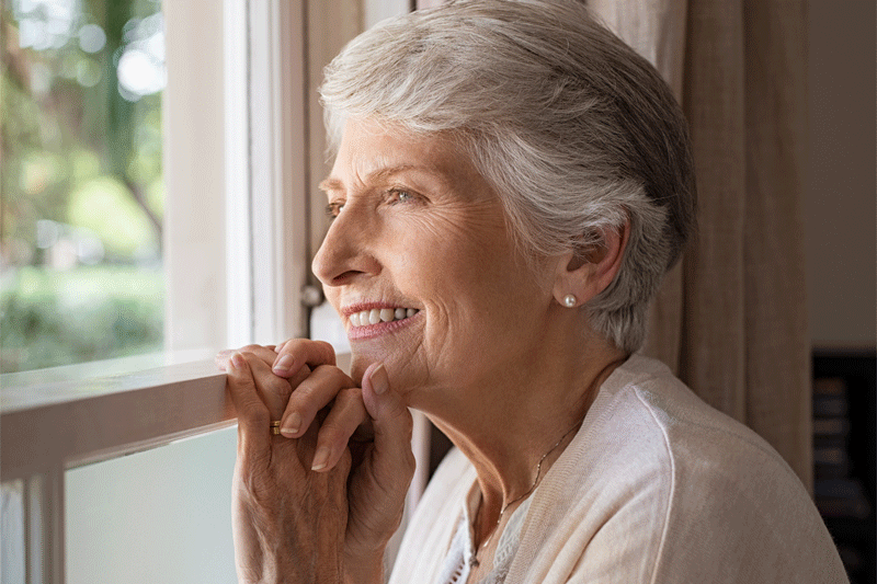 Ältere Frau schaut aus dem Fenster