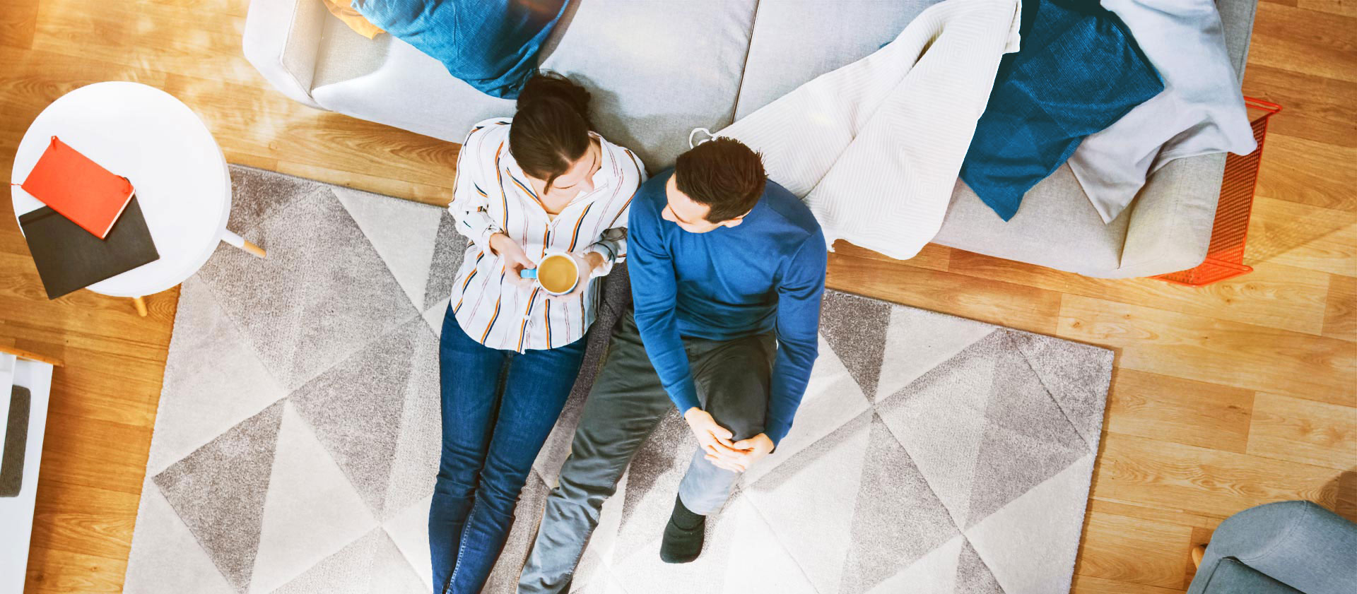 Mann und Frau unterhalten sich gemütlich sitzend auf dem Teppich