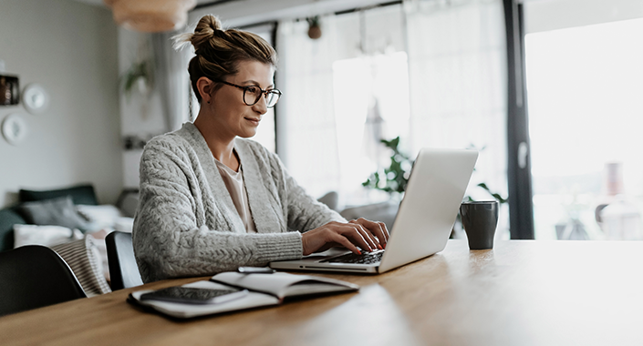 Junge Frau arbeitet zu Hause an ihrem Laptop