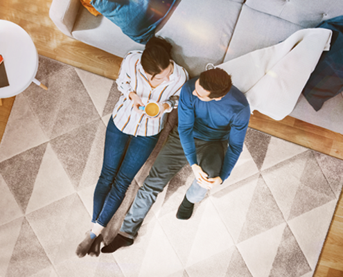 Mann und Frau unterhalten sich gemütlich sitzend auf dem Teppich